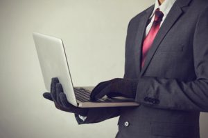 Business man wearing gloves and using computer - fraud, hacker, theft, cyber crime concept
